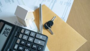 House model, calculator, and keys on documents represent mortgage planning