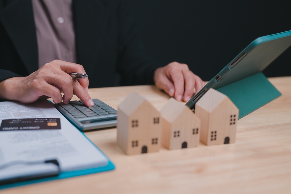 Woman is sitting at a desk with a calculator working on a project involving houses