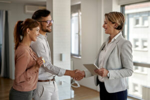 Happy real estate agent and young couple shaking hands after successful agreement