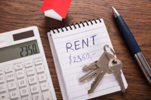 Rent House Concept With Calculated Rental Price On Wooden Desk