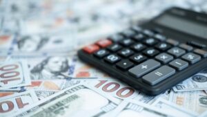 US dollar bills with a calculator, emphasizing financial planning, spending analysis, and money calculations
