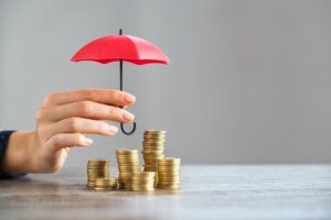 Close up of stack of coins with female hands holding umbrella for protection