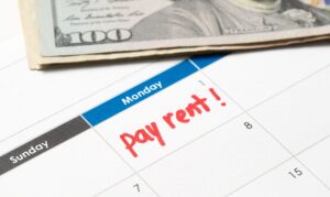 Calendar with the words pay rent written in red ink and with US dollar bills