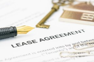 Lease agreement paperwork with house key and pen, representing landlord–tenant contracts in property management