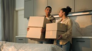 upset woman man with cardboard boxes leave house